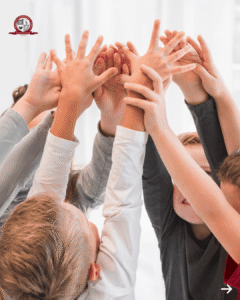 Group of diverse children raising their hands together in a circle to symbolize teamwork and unity
